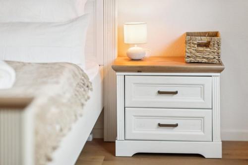 a white nightstand with a lamp on it next to a bed at Alpenzauber Chalet 1 - 6 Personen I Bergblick, Nahe Braunwald - Badewanne, nahe Bahnhof und Parkplatz in Diesbach