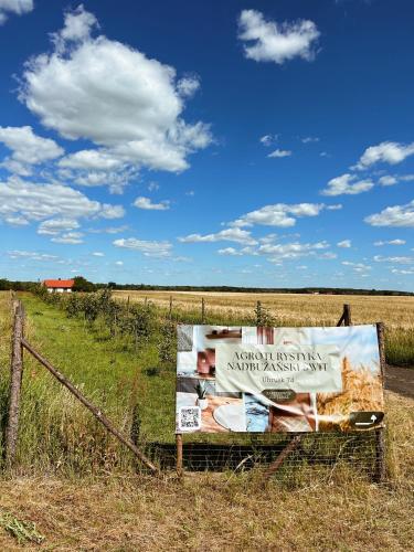 a sign in a field next to a fence at Agroturystyka „Nadbużański Świt” in Wola Uhruska