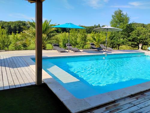 - une piscine avec deux parasols et des chaises dans l'établissement Le Hameau de Galice, à Saint-Sernin