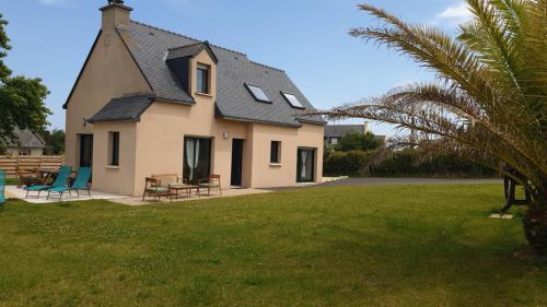 a house with two chairs and a grass yard at Maison de vacances - 6 à 8 personnes in Cléder