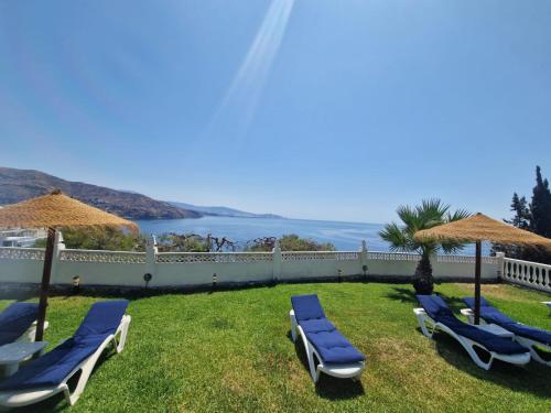 a group of lounge chairs and umbrellas on the grass at las flores in Almuñécar