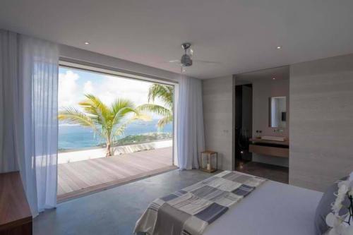 a bedroom with a large window with a view of the ocean at Sparkling Water Villa with Calming Ocean Views in Quartier de Lorient