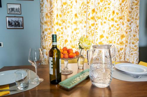 a wooden table with a bottle of wine and glasses at Il Nido di Adele in Gavi