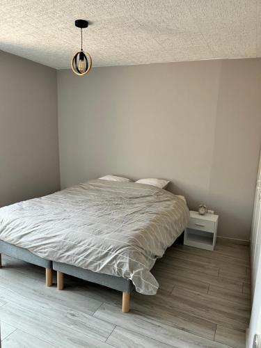 a white bedroom with a bed and a night stand at Au cœur de la Meuse in Damvillers