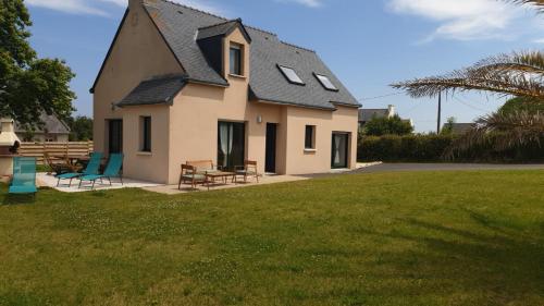 a house with a black roof and chairs in a yard at Maison de vacances - 6 à 8 personnes in Cléder