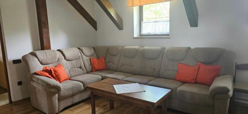 a living room with a gray couch with orange pillows at Chalupa U Zvonka Trojanovice in Frenštát pod Radhoštěm