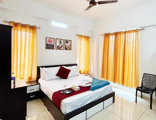 a bedroom with a bed with yellow curtains and a desk at Nestora Suites in Kozhikode