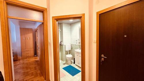 a bathroom with a toilet and a hallway with a door at Budva Summer House in Budva