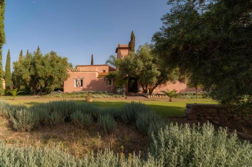a house with a yard with trees and a stone wall at Havre de Paix à Marrakech in Heddad
