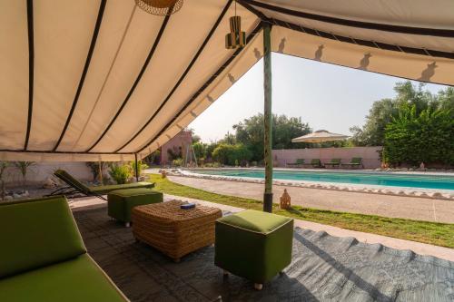a large tent with chairs and a table next to a pool at Havre de Paix à Marrakech in Heddad