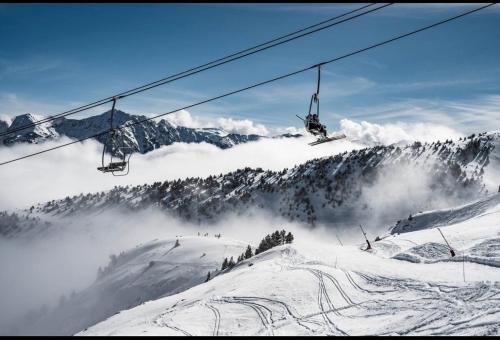 a ski lift flying over a snow covered mountain at Chalet du Parc in Ax-les-Thermes