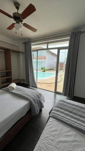 two beds in a bedroom with a view of a pool at Casa Palmar Oceanfront paradise in Zorritos in Zorritos