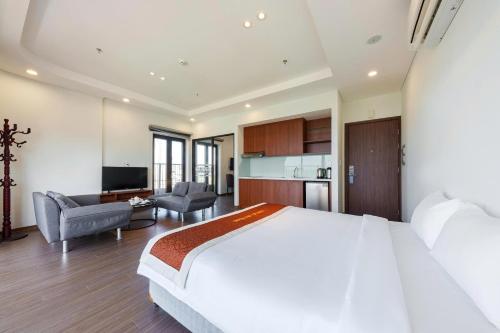 a bedroom with a large white bed and a kitchen at D26 Nha Trang Hotel in Nha Trang
