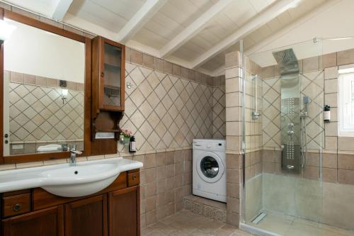 a bathroom with a sink and a washing machine at Villa Moyria by PosarelliVillas in Kassiopi
