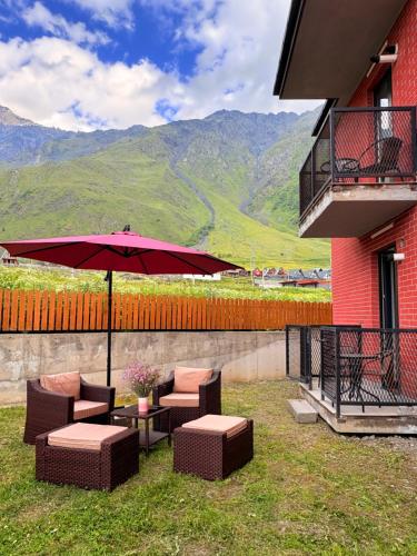 a patio with a table and chairs and an umbrella at Devdaraki Apartments N 113 in Stepantsminda