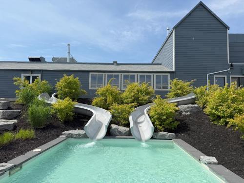 a swimming pool with two slides in front of a house at Condos Vacances MSA - incluant piscine et spas extérieurs chauffés à L'ANNÉE!! in Beaupré