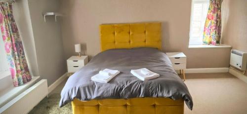 a bedroom with a yellow bed with two towels on it at The Bulls Head Hotel in Youlgreave