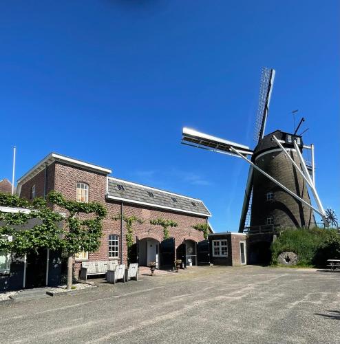 a building with a windmill in front of a building at De Koningsspil - Daar bij die Kempermolen in Breedenbroek