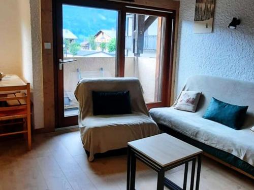 - un salon avec un canapé, une chaise et une fenêtre dans l'établissement Duplex 40m² Les Gets - 6 pers - Pistes Turche 30m - Garage - Navettes gratuites - FR-1-802-82, aux Gets