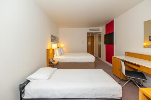 a hotel room with two beds and a desk at DoubleTree by Hilton Hotel London - Tower of London in London