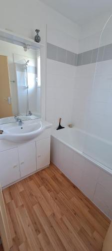 une salle de bain blanche avec un lavabo et un miroir dans l'établissement Maison de vacances avec piscine, à 2 pas de l'océan Atlantique, au Le Verdon-sur-Mer