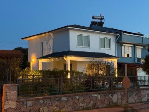 a white house with a fence in front of it at Relaxing Stay by the Beach in Ayvalık