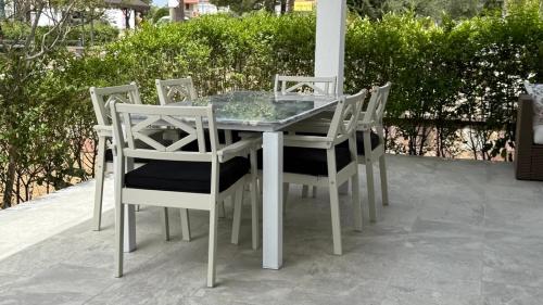 a glass table and four white chairs on a patio at Relaxing Stay by the Beach in Ayvalık