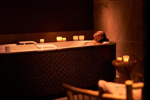 a woman sitting in a bath tub in a bathroom at Lighthouse Hotel & Spa in Büsum