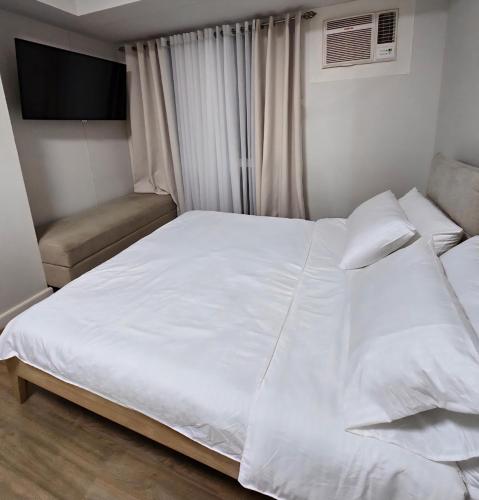 a bedroom with a large white bed and a chair at Ayala Cebu Solinea in Cebu City