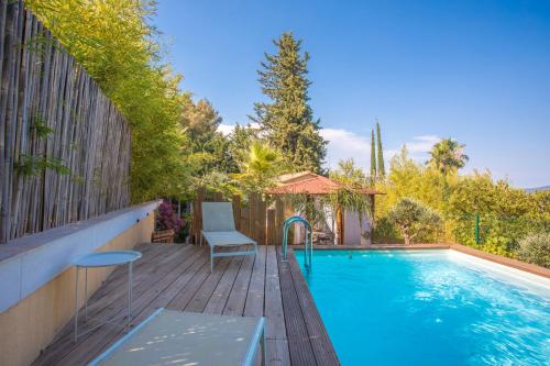 - une piscine avec une table et des chaises sur une terrasse en bois dans l'établissement Palmiers en couleurs, à Cuers