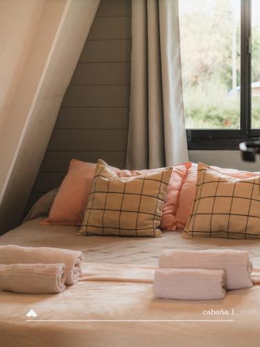 a bed with pillows on it with a window at COMPLEJO ISABELLA in Villa Amancay