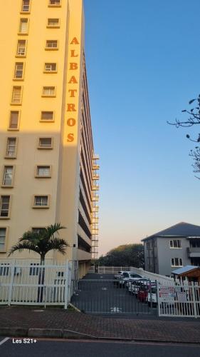 a tall yellow building next to a parking lot at Albatros 506 in Amanzimtoti