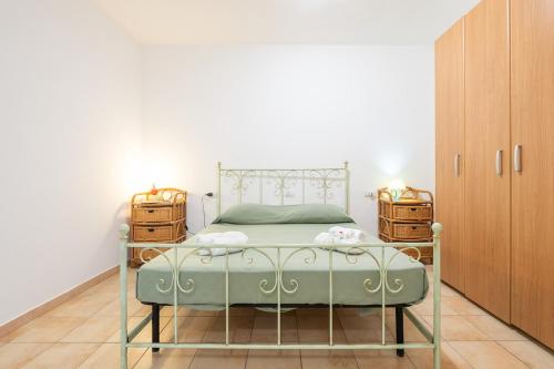 a bedroom with a green bed and wooden cabinets at AffittaSardegna - Domo Pineta in Santa Lucia