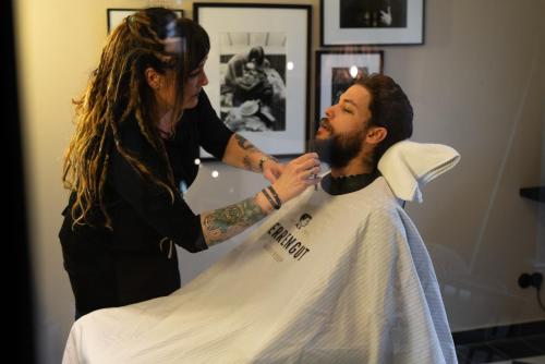 a woman cutting a mans beard in a barber shop at Lighthouse Hotel & Spa in Büsum