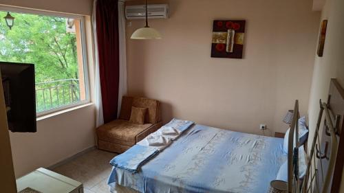 a bedroom with a bed and a window and a chair at Вила Фернандес in Chernomorets