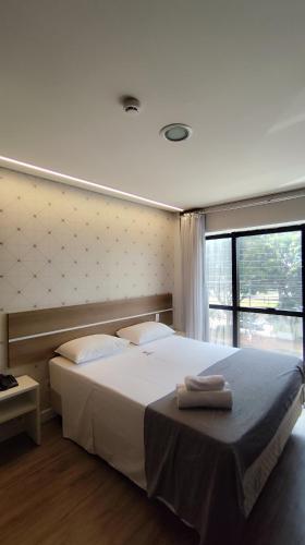 a bedroom with a large white bed and a window at Assay Plaza Hotel in Hortolândia