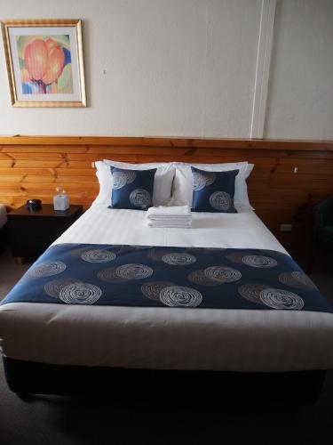 a bedroom with a large bed with blue sheets and pillows at Majestic Motel in Horsham