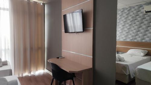 a room with a desk and a bedroom with two beds at Assay Plaza Hotel in Hortolândia