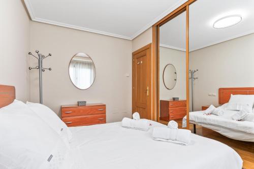ein Schlafzimmer mit zwei Betten und einem Spiegel in der Unterkunft Apartamento Avenida del Mar in Oviedo