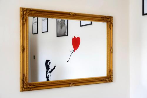 a mirror with a picture of a man with a red umbrella at STR8BS8 Georgian 2-Bedroom Apartment, Clifton, Parking & Garden in Bristol