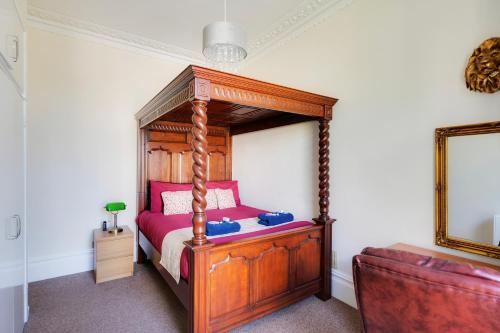 a bedroom with a wooden canopy bed with pink sheets at STR8BS8 Georgian 2-Bedroom Apartment, Clifton, Parking & Garden in Bristol