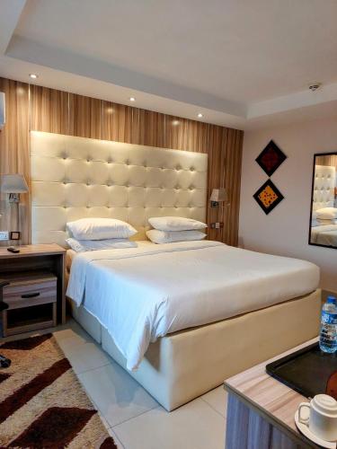 a bedroom with a large bed with a large headboard at Golden Tulip Hotel Port Harcourt -GTPH in Port Harcourt