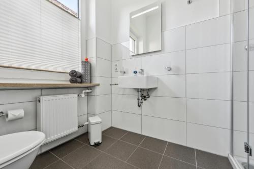 a white bathroom with a sink and a toilet at Diepholzer Boardinghouse by BohnApartments - Parkplätze - WLAN - Garten - ruhig in Diepholz