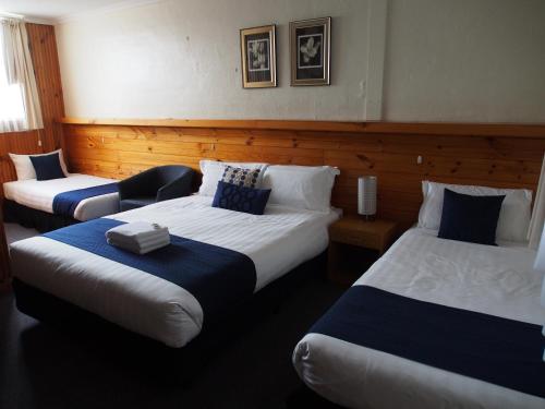 a hotel room with two beds with blue and white sheets at Majestic Motel in Horsham