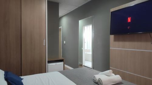 a bedroom with a bed and a tv on the wall at Assay Plaza Hotel in Hortolândia