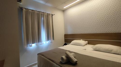 a bedroom with a bed with two towels on it at Assay Plaza Hotel in Hortolândia