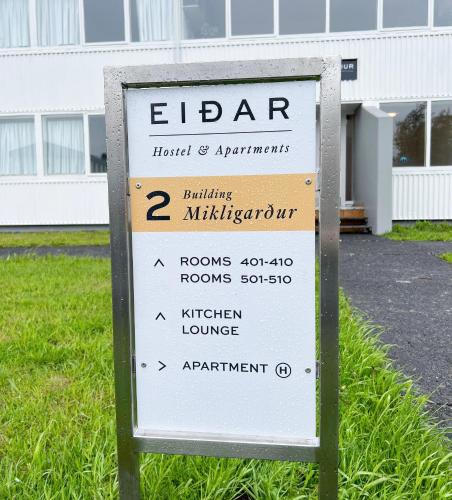 a sign in the grass in front of a building at Eiðar - Hostel in Eiðar