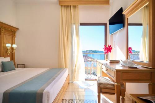 a bedroom with a bed and a desk and a window at EVLOGIA HOTEL SEAFRONT and ANEX by Greek Pride in Fourka