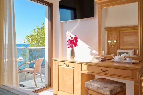 a bedroom with a desk with a mirror and a balcony at EVLOGIA HOTEL SEAFRONT and ANEX by Greek Pride in Fourka