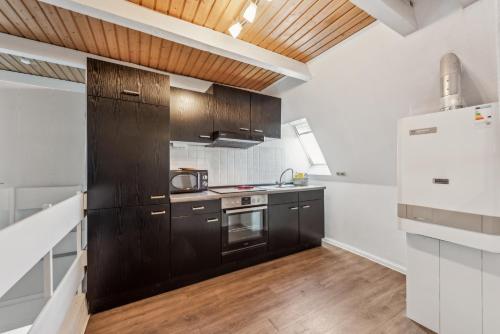 a kitchen with black cabinets and a refrigerator at Diepholzer Boardinghouse by BohnApartments - Parkplätze - WLAN - Garten - ruhig in Diepholz